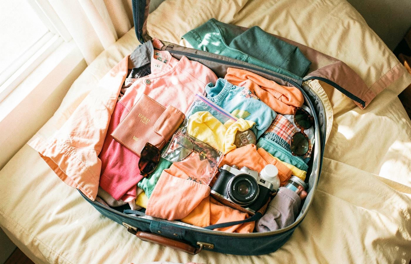An open suitcase packed with colorful vacation essentials